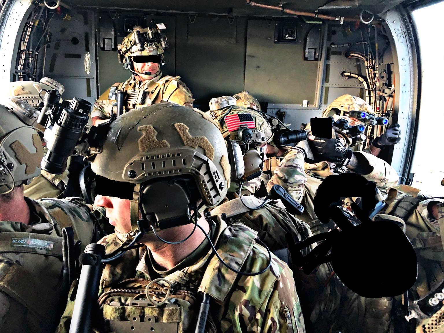 Operators seated aboard a helicopter, faces obscured